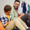 A male teacher and young student sitting on a hallway floor to engage in learning, supported by effective school Medicaid billing in Iowa.